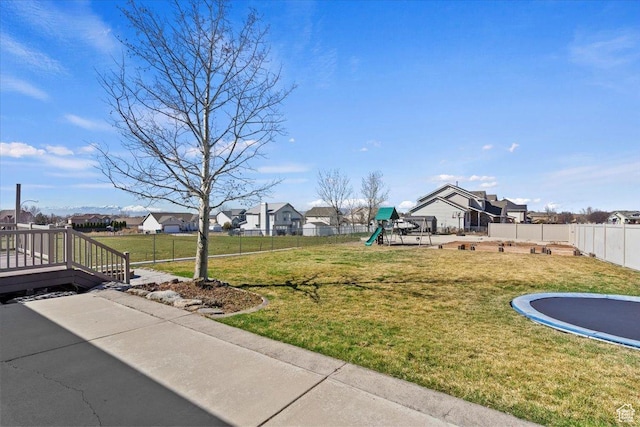 view of yard featuring a playground, a residential view, fence, and a trampoline