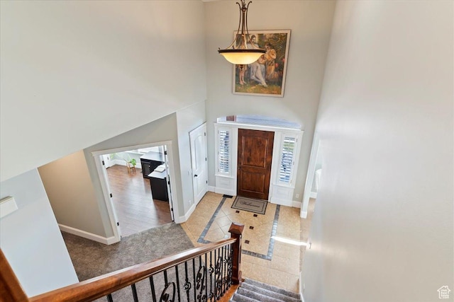 foyer featuring baseboards, a towering ceiling, and tile patterned floors