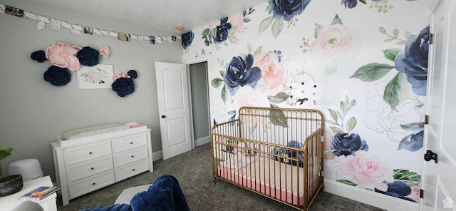 bedroom featuring a nursery area, dark carpet, and baseboards