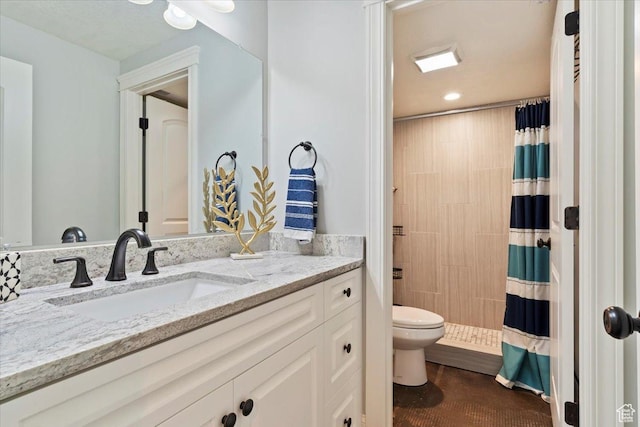 full bathroom with toilet, tiled shower, and vanity