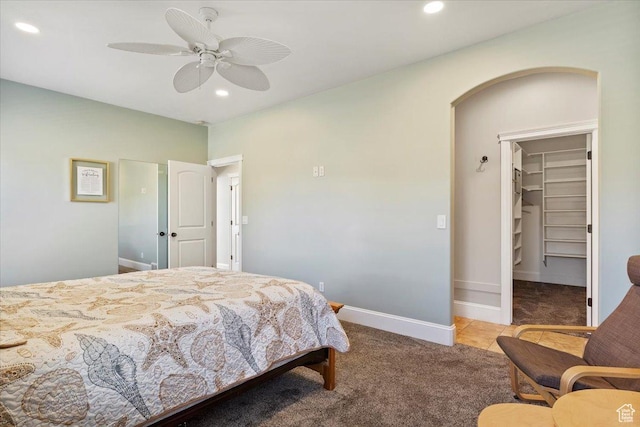 carpeted bedroom featuring a walk in closet, baseboards, arched walkways, and recessed lighting
