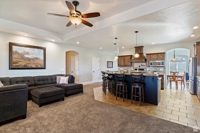 living area featuring light tile patterned flooring, ceiling fan, recessed lighting, light carpet, and arched walkways