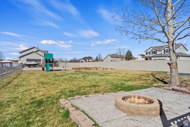 view of yard with a fenced backyard, a fire pit, a patio, and a residential view