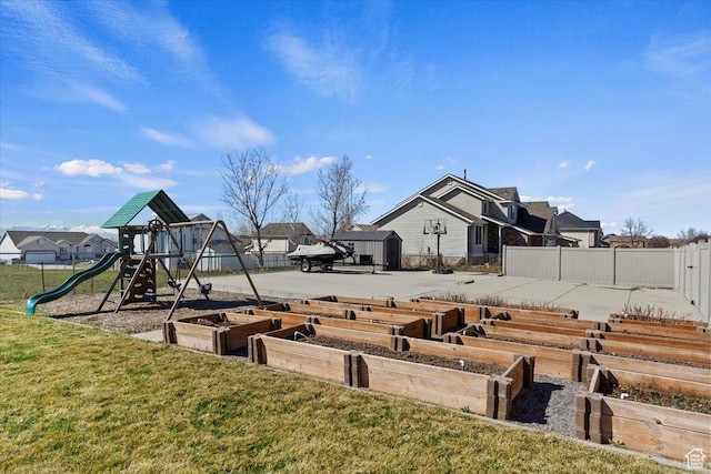 view of yard featuring a vegetable garden, playground community, and fence