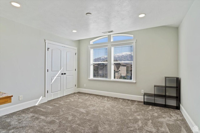 interior space featuring recessed lighting, carpet flooring, baseboards, a textured ceiling, and visible vents