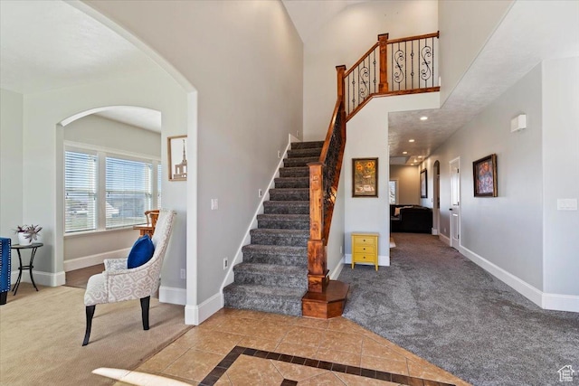 stairs featuring carpet floors, baseboards, and a towering ceiling