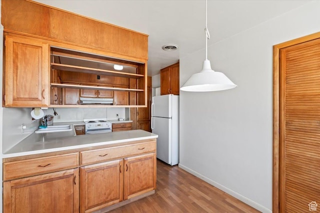 kitchen featuring a sink, open shelves, under cabinet range hood, white appliances, and visible vents