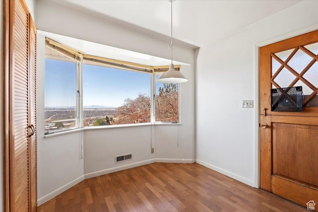 unfurnished dining area featuring baseboards, visible vents, and wood finished floors