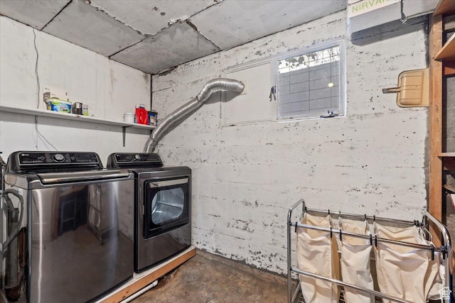clothes washing area with washer and dryer and concrete block wall