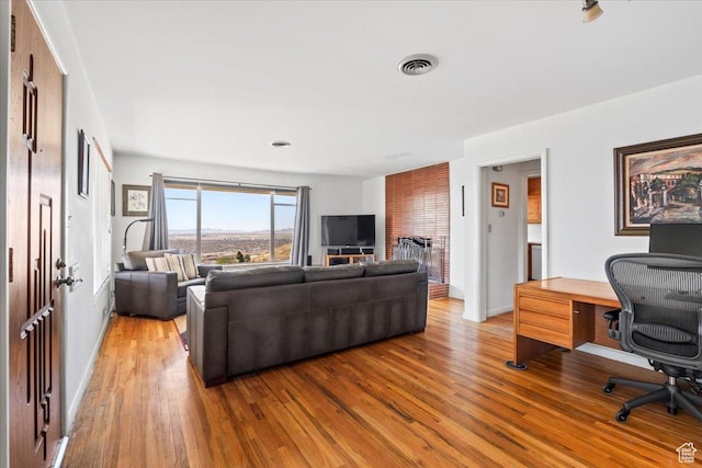 living room with baseboards, visible vents, and wood finished floors