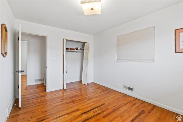 unfurnished bedroom featuring a closet, visible vents, and wood finished floors