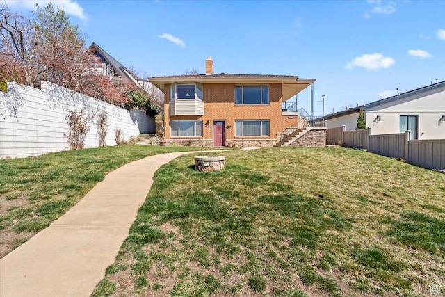 back of property featuring stairs, a chimney, fence, and a lawn
