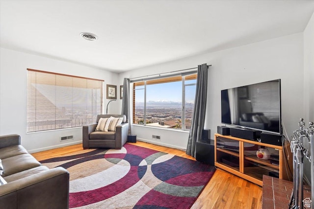 living room featuring baseboards, visible vents, and wood finished floors