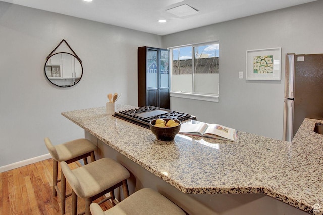 650 N 300 W Unit 202, Salt Lake City, UT 84103 - kitchen featuring freestanding refrigerator, light stone countertops, a breakfast bar area, and light wood-type flooring