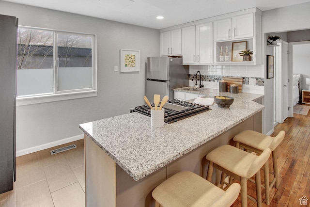 650 N 300 W Unit 202, Salt Lake City, UT 84103 - kitchen featuring backsplash, freestanding refrigerator, a peninsula, visible vents, and white cabinets