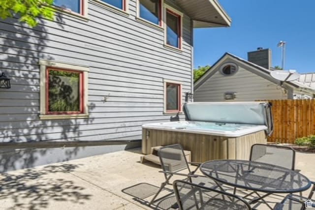 view of patio featuring a hot tub, fence, and outdoor dining space