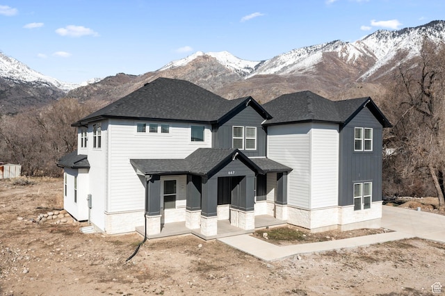 modern inspired farmhouse with a shingled roof, covered porch, and a mountain view
