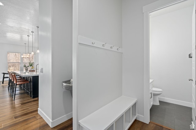 mudroom featuring a notable chandelier, dark wood-style floors, and baseboards