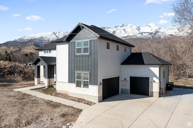 view of home's exterior featuring stone siding, board and batten siding, driveway, and a mountain view