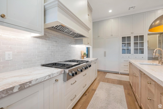 775 W 1300 S, Hurricane, UT 84737 - kitchen featuring custom exhaust hood, a sink, stainless steel gas stovetop, light stone counters, and light wood-type flooring