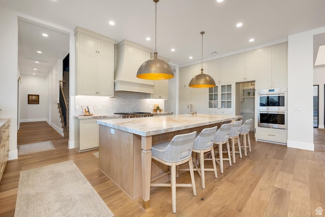 775 W 1300 S, Hurricane, UT 84737 - kitchen with stainless steel double oven, premium range hood, decorative backsplash, baseboards, and a large island with sink