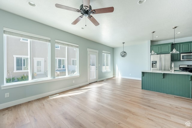607 N Glenwilde Rd Unit 116, Vineyard, UT 84059 - unfurnished living room featuring a ceiling fan, light wood-style flooring, a healthy amount of sunlight, and visible vents