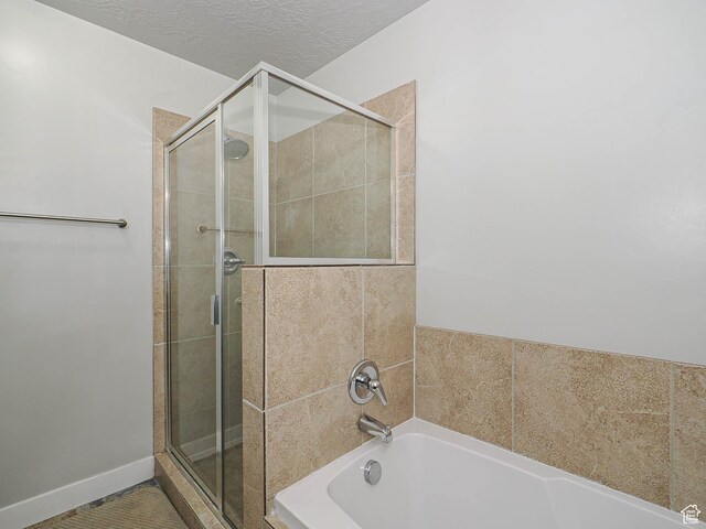 2291 E Ox Yoke Dr N, Eagle Mountain, UT 84005 - full bathroom featuring a textured ceiling, baseboards, a garden tub, and a shower stall