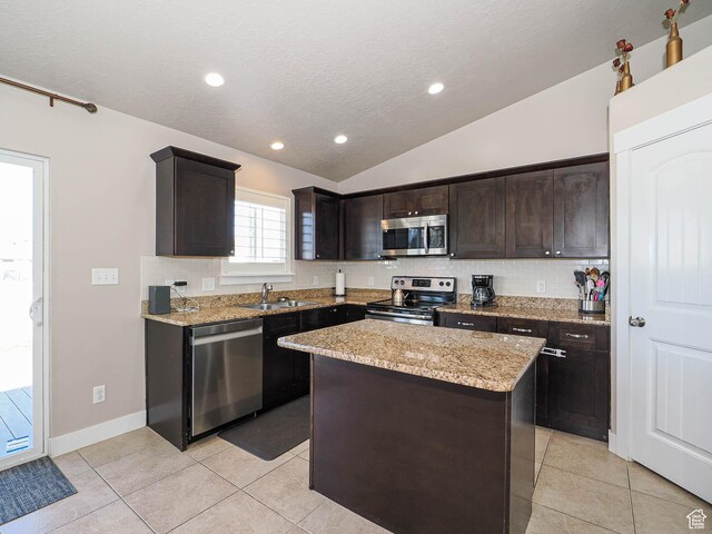 2291 E Ox Yoke Dr N, Eagle Mountain, UT 84005 - kitchen featuring vaulted ceiling, dark brown cabinetry, a sink, tasteful backsplash, and appliances with stainless steel finishes