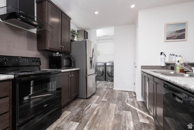 kitchen with dark brown cabinets, under cabinet range hood, a sink, black appliances, and separate washer and dryer