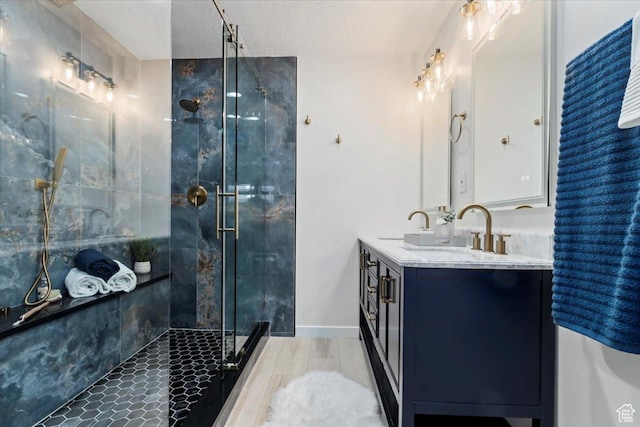 full bath featuring double vanity, a sink, a stall shower, and baseboards