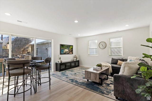 living area with a healthy amount of sunlight, recessed lighting, light wood-style floors, and visible vents