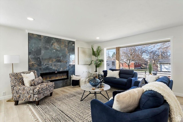 living area featuring baseboards, a fireplace, wood finished floors, and recessed lighting