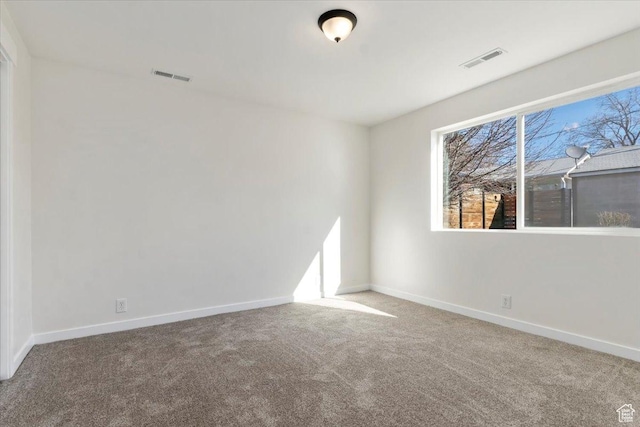 spare room with carpet floors, baseboards, and visible vents