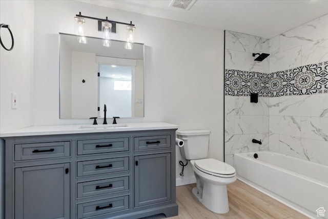 bathroom featuring visible vents, toilet, wood finished floors, vanity, and shower / bathtub combination