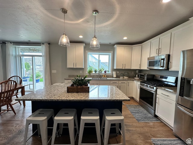 2685 E White Birch Dr, Eagle Mountain, UT 84005 - kitchen with stainless steel appliances, a sink, a kitchen island, a breakfast bar, and a textured ceiling