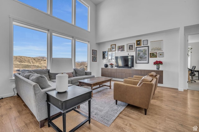 2685 E White Birch Dr, Eagle Mountain, UT 84005 - living area featuring light wood-style floors, a towering ceiling, and baseboards