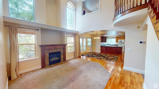14313 S Murdoch Peak Dr, Herriman, UT 84096 - living room with arched walkways, a towering ceiling, light wood finished floors, a tiled fireplace, and a chandelier
