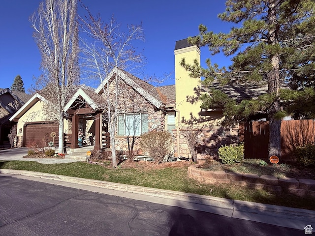 6991 S Canyon Pines Cir E, Cottonwood Heights, UT 84121 - view of front of house with stone siding, fence, an attached garage, a chimney, and concrete driveway