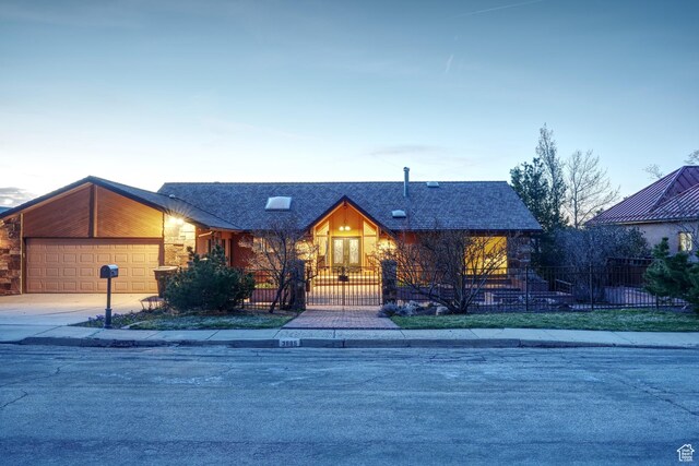 view of front of property featuring an attached garage, a fenced front yard, concrete driveway, and roof with shingles