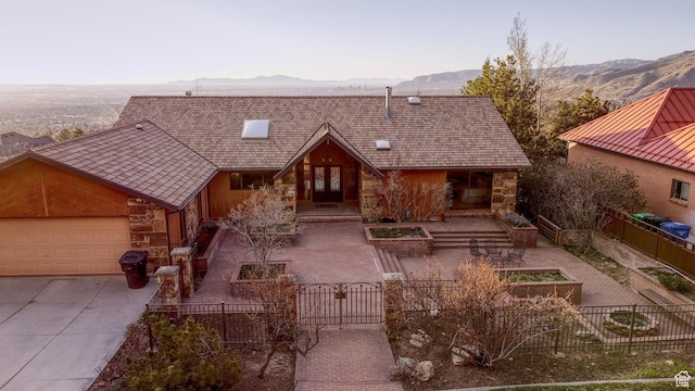 3885 E Viewcrest Dr, Millcreek, UT 84124 - view of front of property featuring a mountain view, stone siding, a fenced front yard, a gate, and driveway