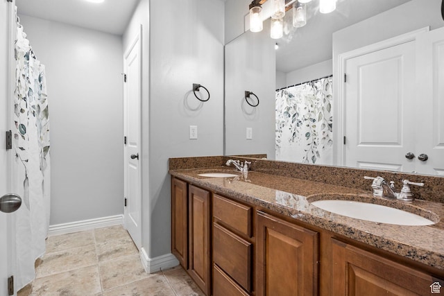 bathroom featuring double vanity, baseboards, a sink, and tile patterned floors