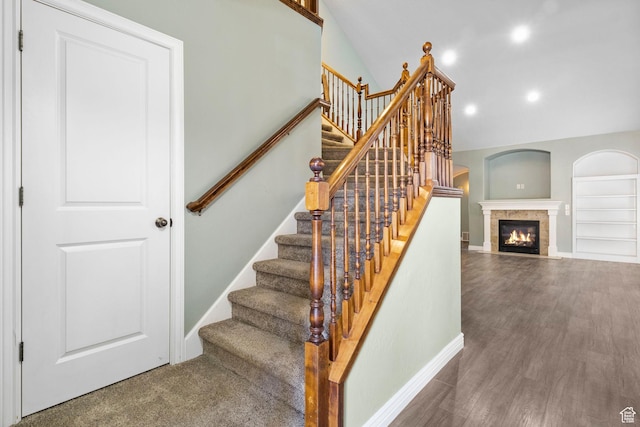 stairs featuring vaulted ceiling, a fireplace with flush hearth, wood finished floors, baseboards, and recessed lighting