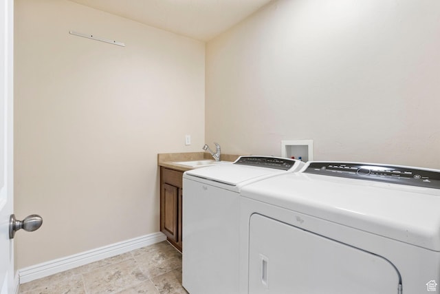 clothes washing area featuring baseboards, washing machine and dryer, cabinet space, and a sink