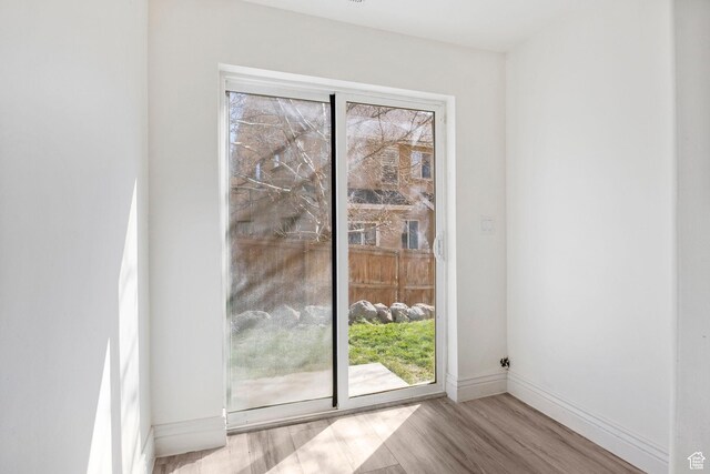 doorway to outside featuring baseboards and wood finished floors
