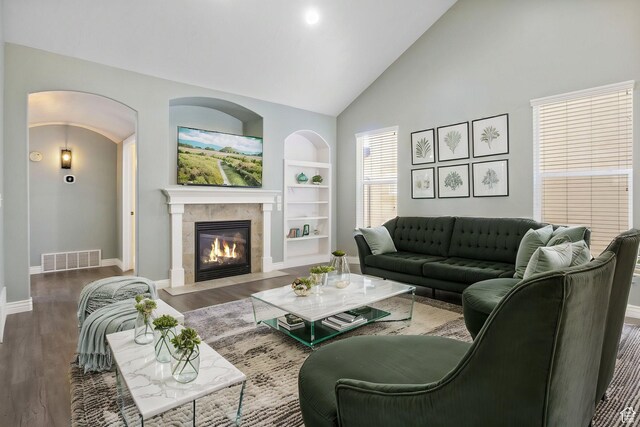 living room featuring built in shelves, visible vents, a tiled fireplace, and wood finished floors