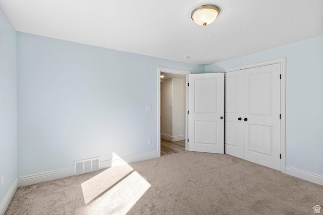 unfurnished bedroom with baseboards, visible vents, a closet, and carpet flooring