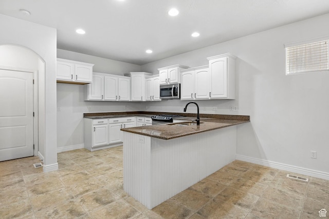 kitchen featuring a sink, appliances with stainless steel finishes, a peninsula, visible vents, and white cabinets