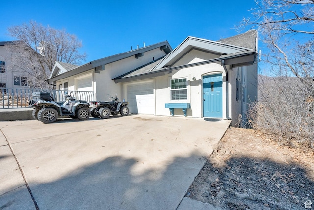 exterior space featuring roof with shingles, stucco siding, an attached garage, and concrete driveway