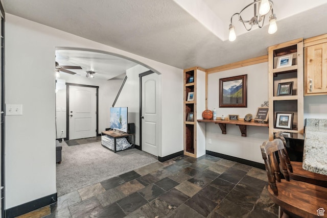 483 N 2650 W Unit 6, Tremonton, UT 84337 - interior space with stone finish floor, baseboards, a ceiling fan, arched walkways, and dark colored carpet