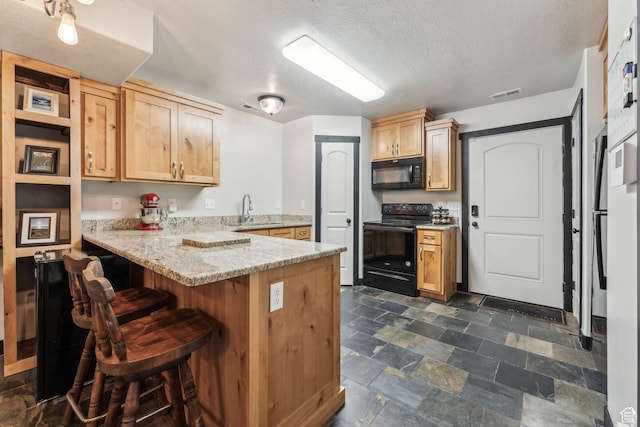 483 N 2650 W Unit 6, Tremonton, UT 84337 - kitchen featuring a breakfast bar area, a sink, a peninsula, stone finish flooring, and black appliances